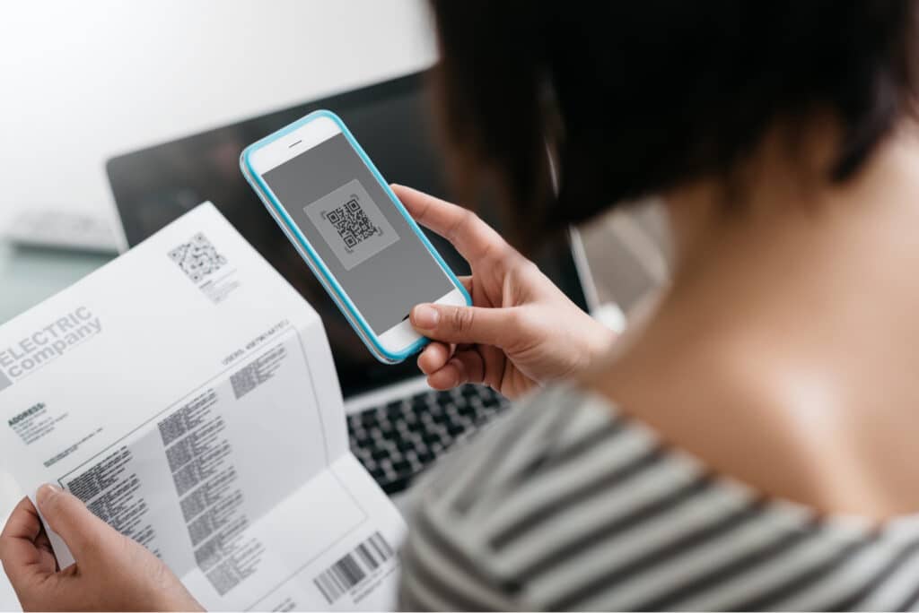 Mulher pagando conta com o celular usando QR code
