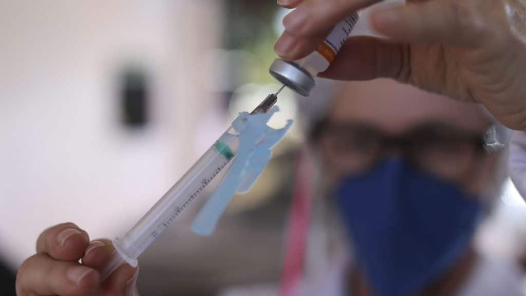 Enfermeira carregando dose de vacina em agulha de injeção