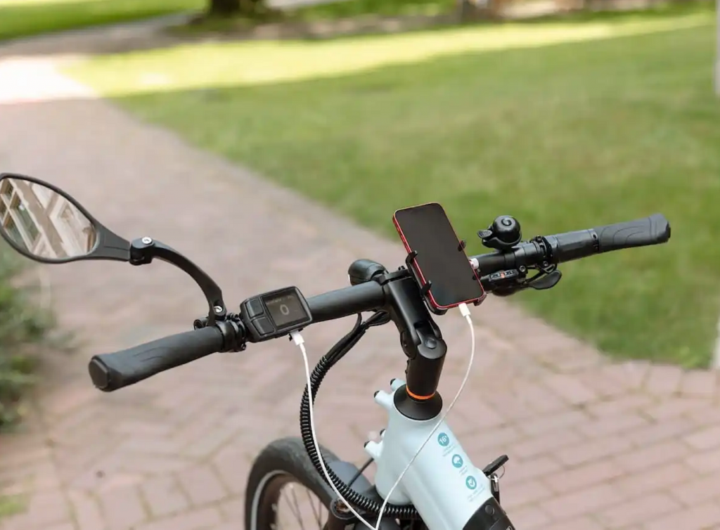 Imagem mostra o guidão de uma bicicleta elétrica, com visor LCD e um apoio para celular