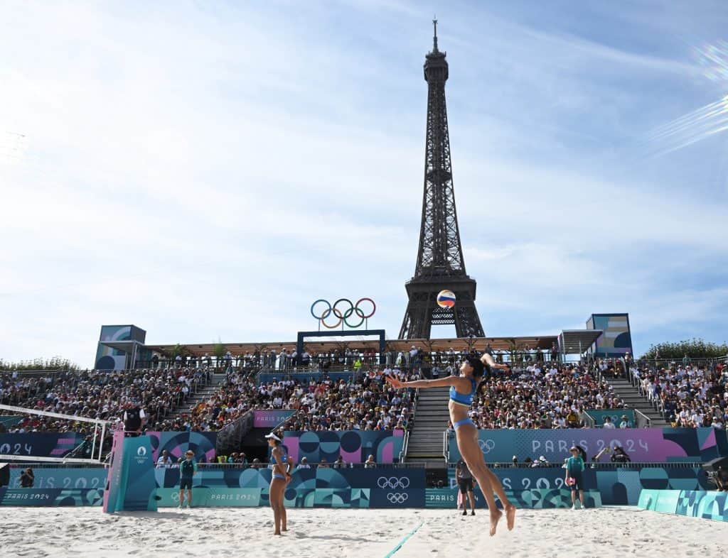 atletas praticam vôlei de praia com a torre eiffel ao fundo