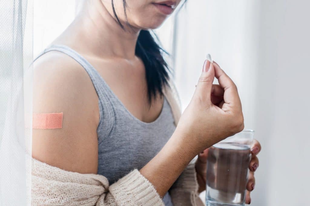 Mulher tomando paracetamol depois da vacina