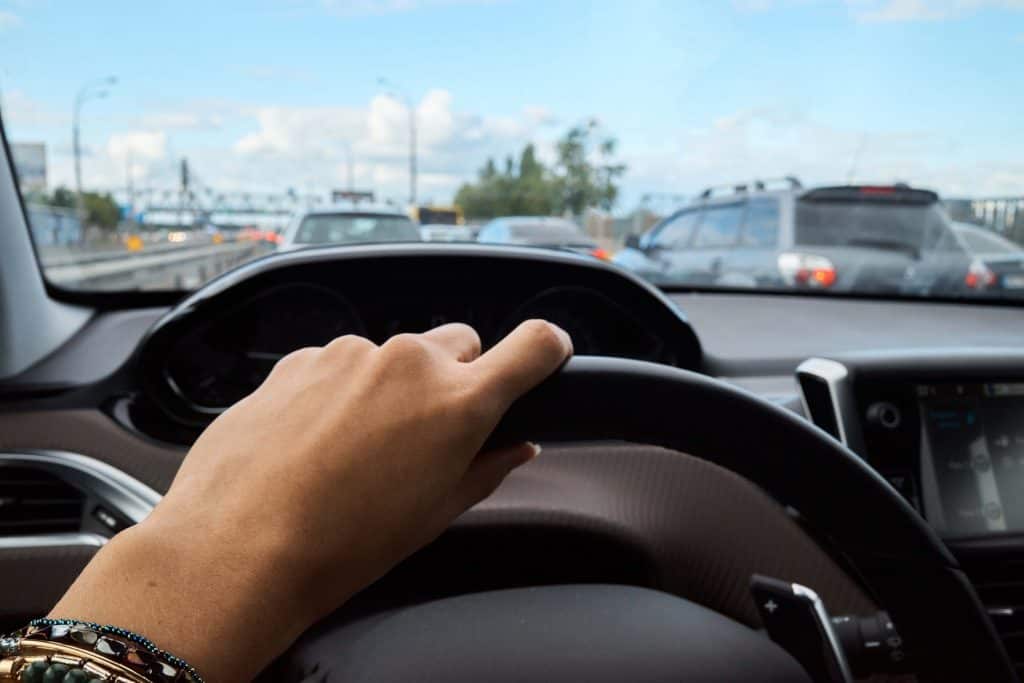 Pessoa com a mão no volante em trânsito